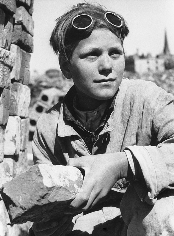 Ein Junge hält einen Ziegelstein in den Händen, hilft beim Wiederaufbau