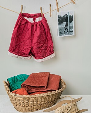 Selbstgenähte Fußballhose aus einer roten Steppdecke, daneben ein Foto mit jugendlichem Torwart in einer solchen Hose Anfang der 1950er Jahre